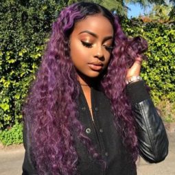 justine sky with long purple curly hair posing outside