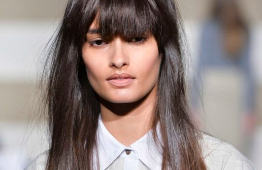 woman on the runway with long dark brown hair worn straight and with a full fringe cut in