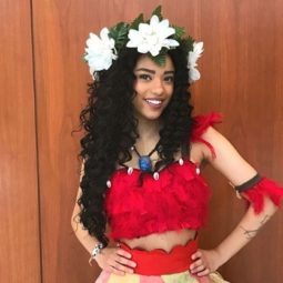 Disney hairstyles: Photo of a cosplayer dressed as Disney's Moana with long curly dark hair and oversized white floral crown