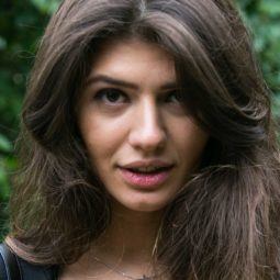 best conditioner for thick hair: close up shot of woman with thick hair, wearing black jacket and satin shirt